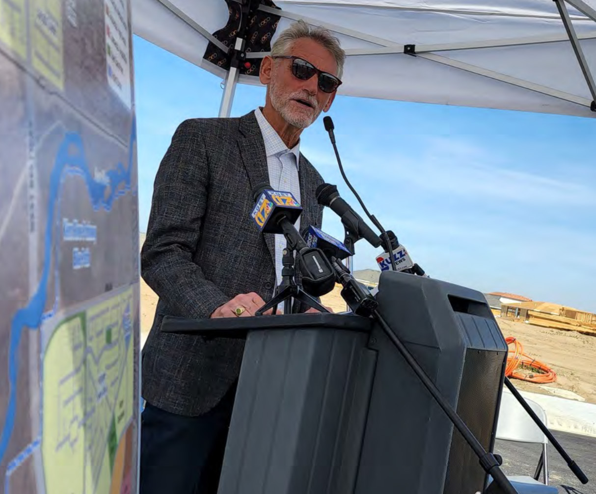Bob Smith speaking at a podium with local news microphones